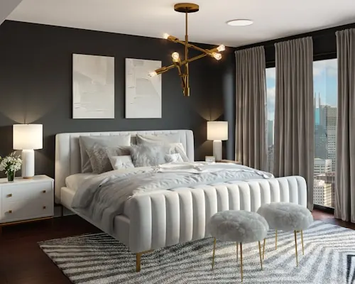 Bedroom with charcoal walls, a channel-tufted white bed, brass chandelier and fur stools