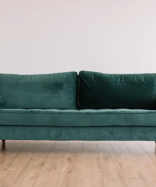 Emerald velvet sofa against a pale wall on light oak flooring