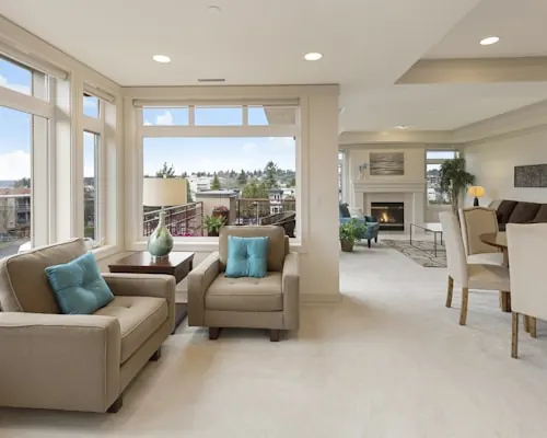 Bright living room with beige sofas, teal cushions and tall windows