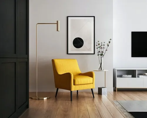 Mustard yellow armchair and brass floor lamp beside a dark doorway