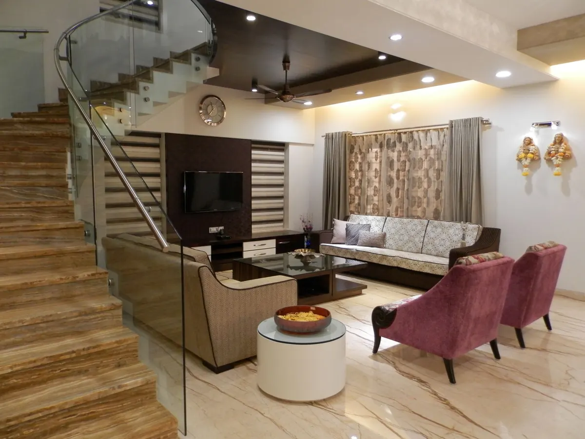 Living room with glass-railed staircase, textured feature wall and plum armchairs