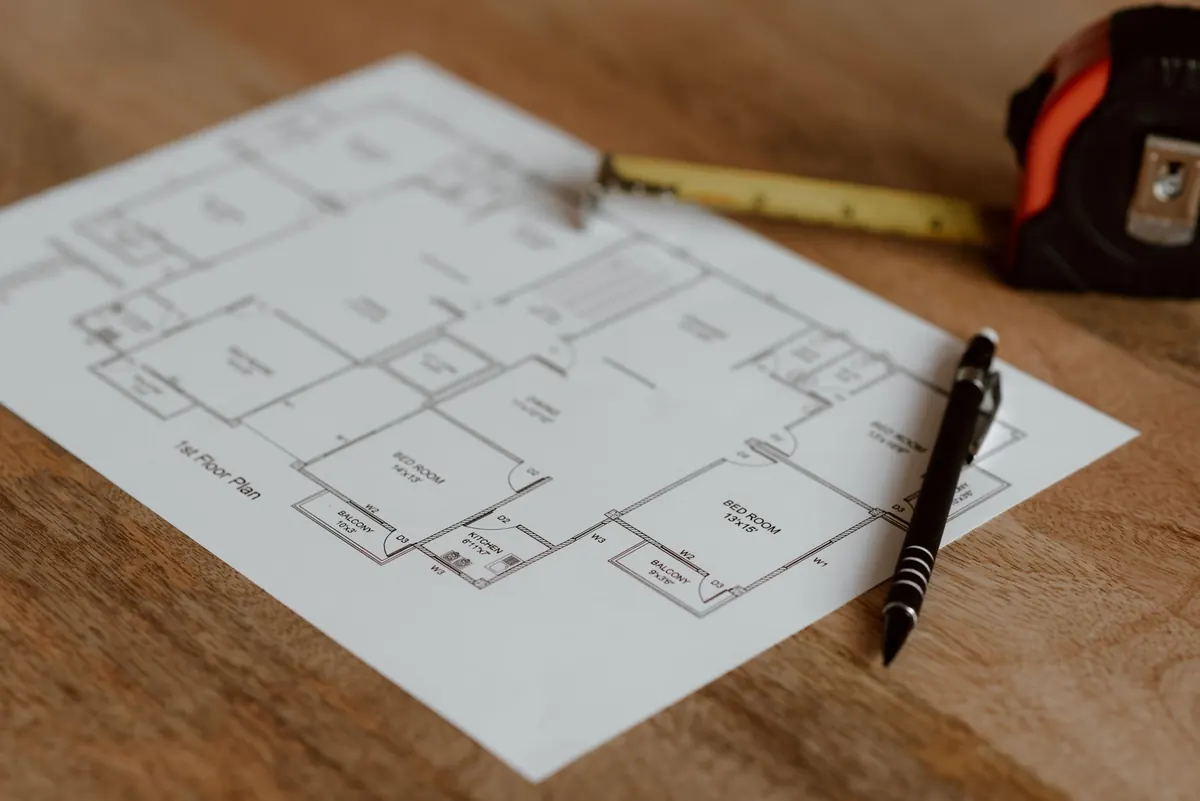 Printed floor plan with a pen and measuring tape on a timber desk