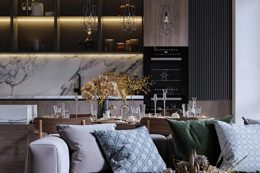 Dark wood-finish kitchen wall with backlit open shelves, black fluted panels and a white marble backsplash, seen behind a grey sofa with patterned cushions