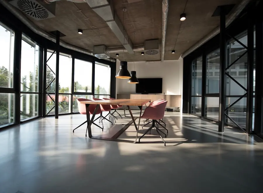 Double-height office with black steel glazing, polished concrete floor and a long timber meeting table