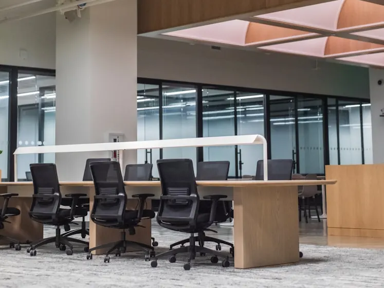 Open-plan office with timber workstations, black task chairs and glass meeting rooms