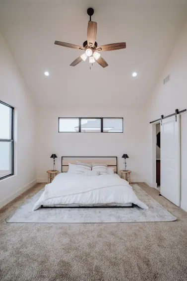 Ceiling fan with timber-finish blades and a light kit in a white bedroom