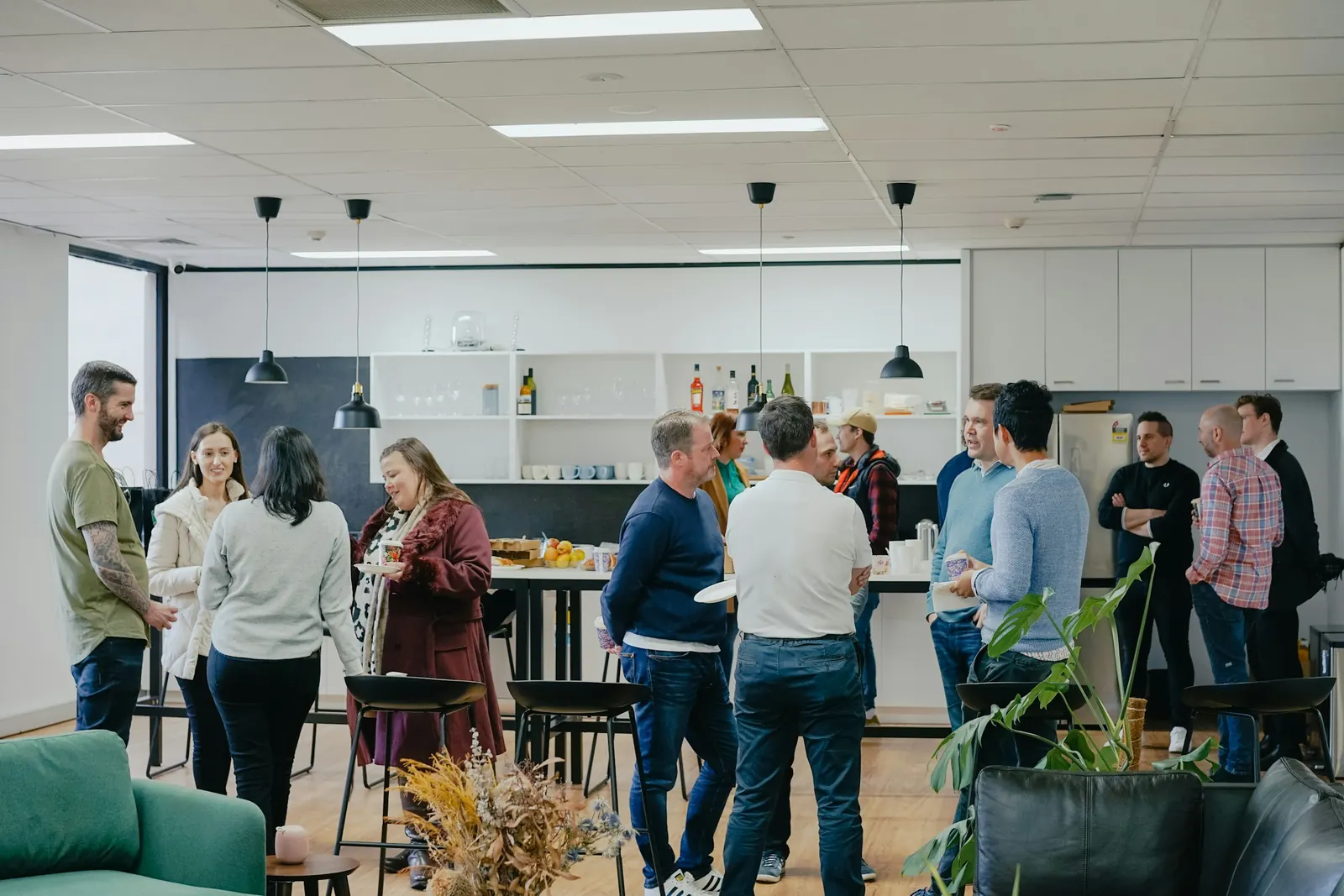 A studio team chatting over coffee in a bright open-plan kitchen