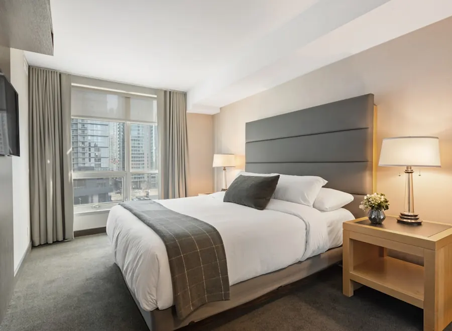 Finished bedroom with a tall upholstered headboard, crisp bedding and warm bedside lamps